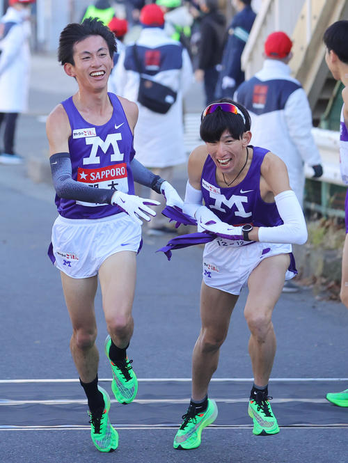 明大1区の富田は、トップで2区小沢にたすきをつなぐ（撮影・野上伸悟）
