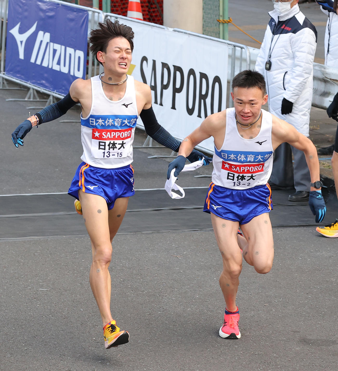 第98回箱根駅伝　たすきをつなぐ日体大1区高津浩揮（左）と2区藤本珠輝（2022年1月2日撮影）