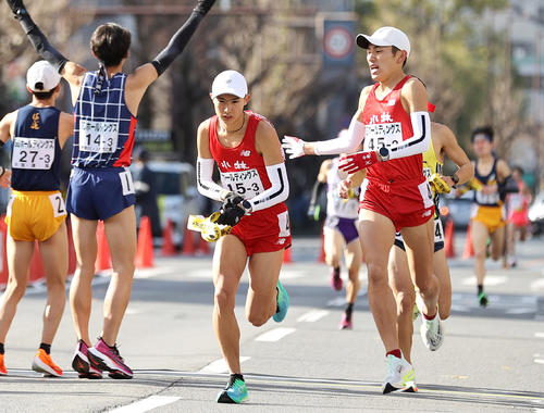 小林3区佐藤（左から3人目）は2区服部（右）からたすきを受け取り走り出す（撮影・上山淳一）