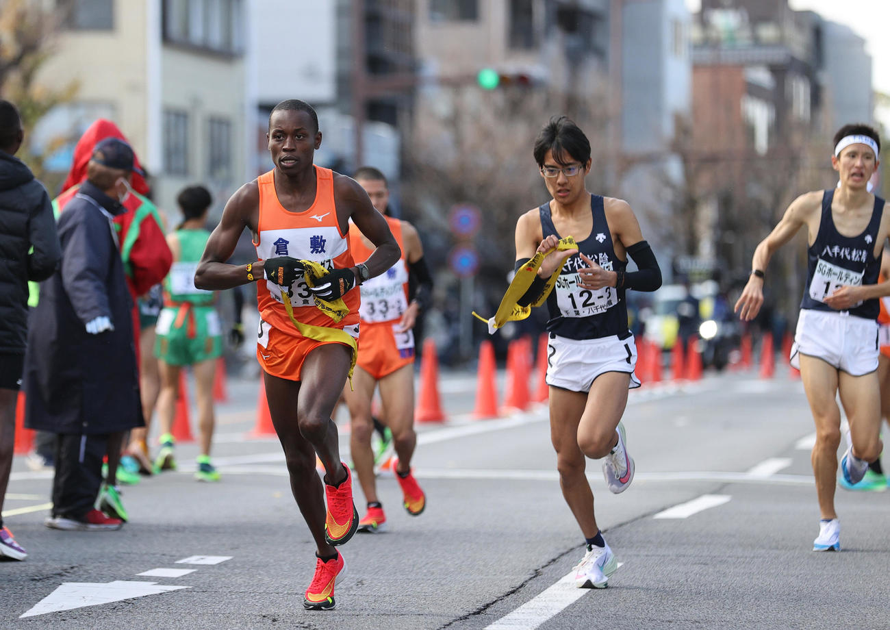 倉敷3区サムエル（手前）はたすきを受け取り走り出す（撮影・上山淳一）