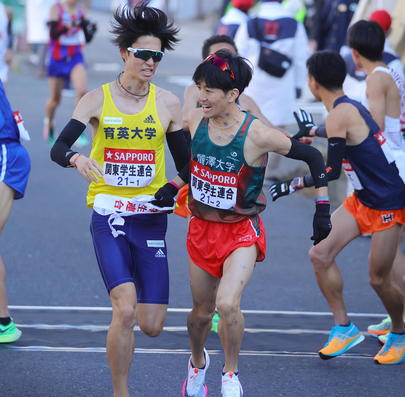 3位相当のタイムで2区麗沢大・工藤（右）たすきをつなぐ関東学生連合1区の育英大・新田（撮影・野上伸悟）