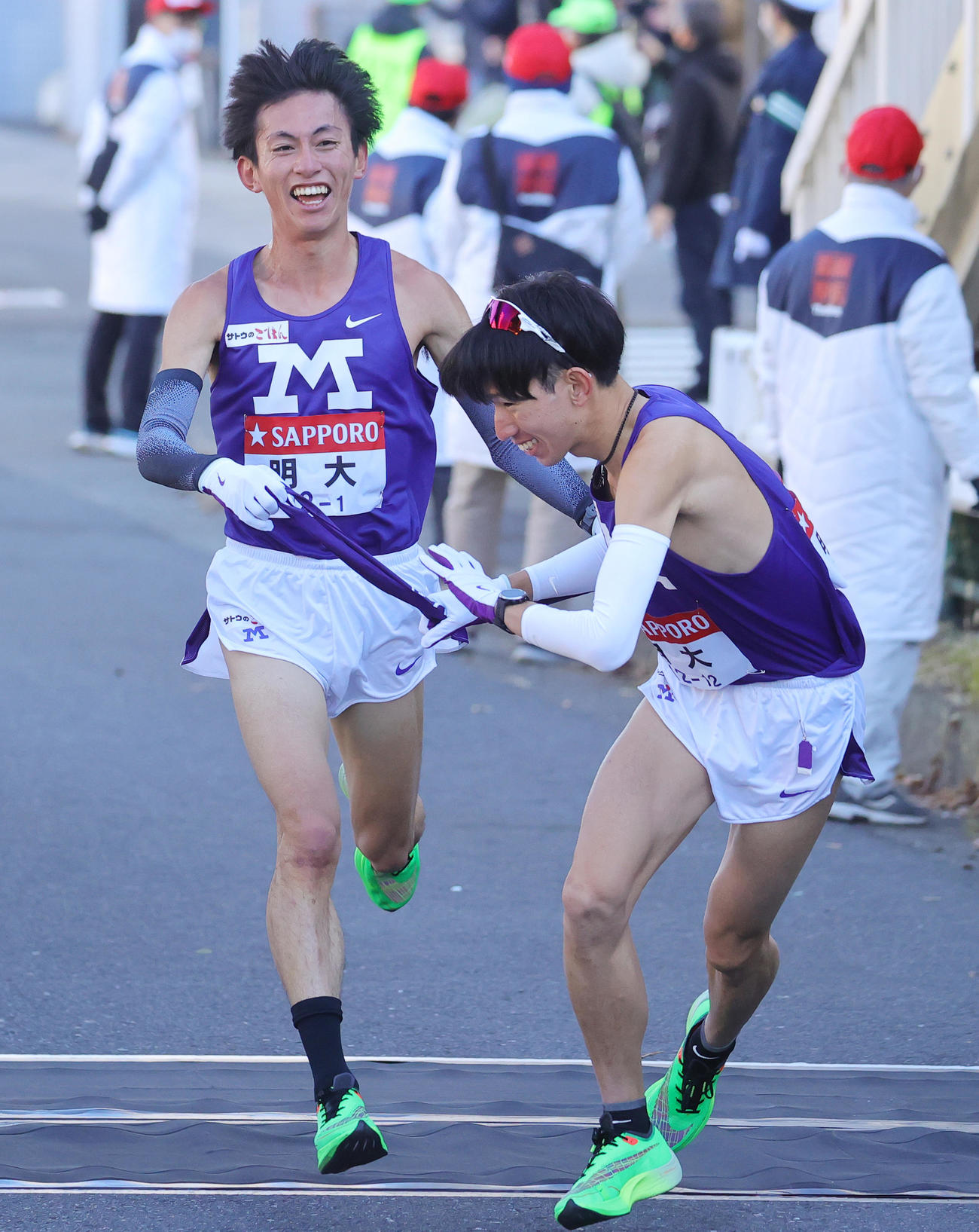 明大1区の富田は、トップで2区小沢にたすきをつなぐ（撮影・野上伸悟）