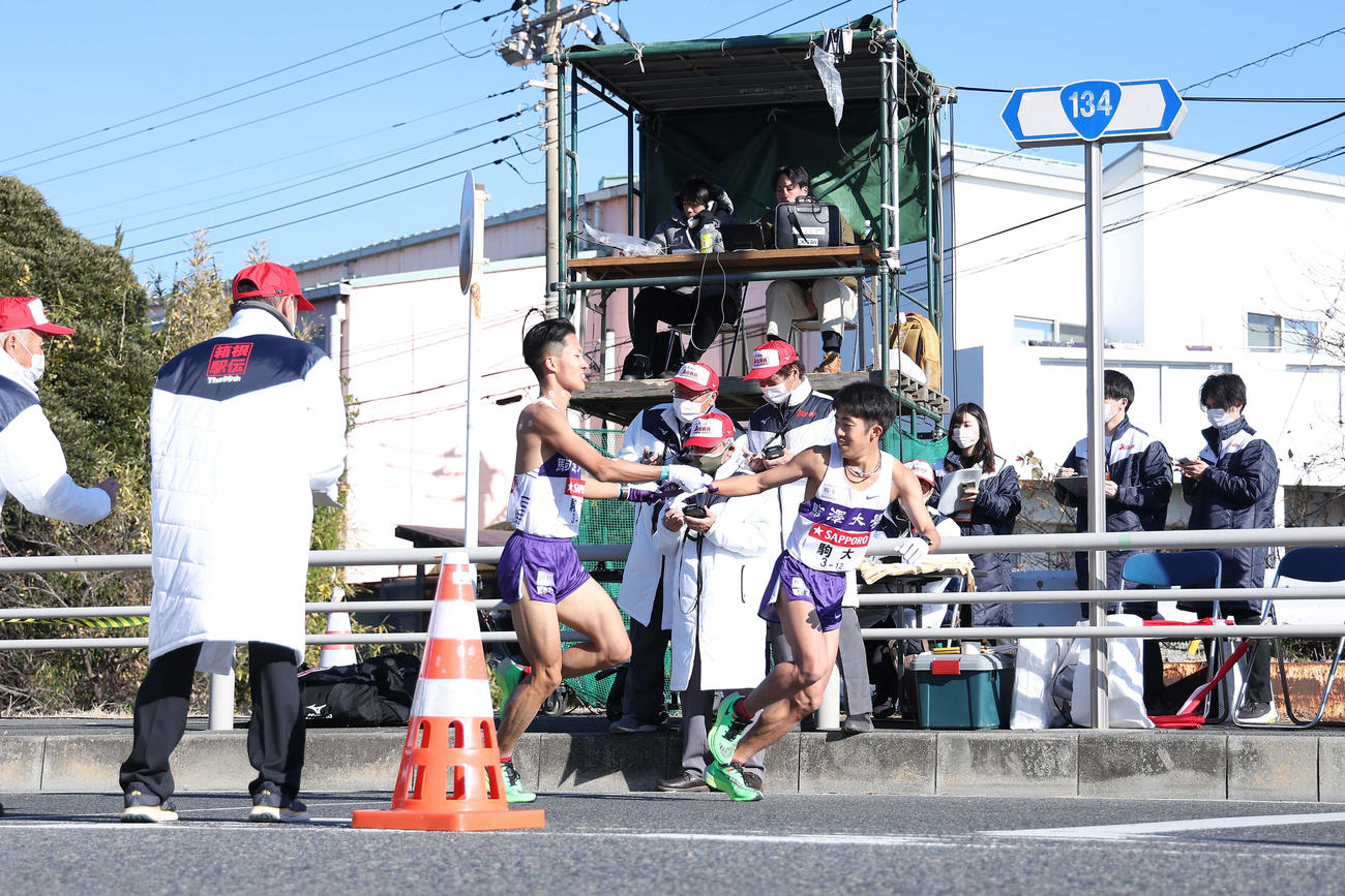 平塚中継所、1位でたすきをつなぐ駒大7区安原（左）と8区赤星（撮影・河田真司）