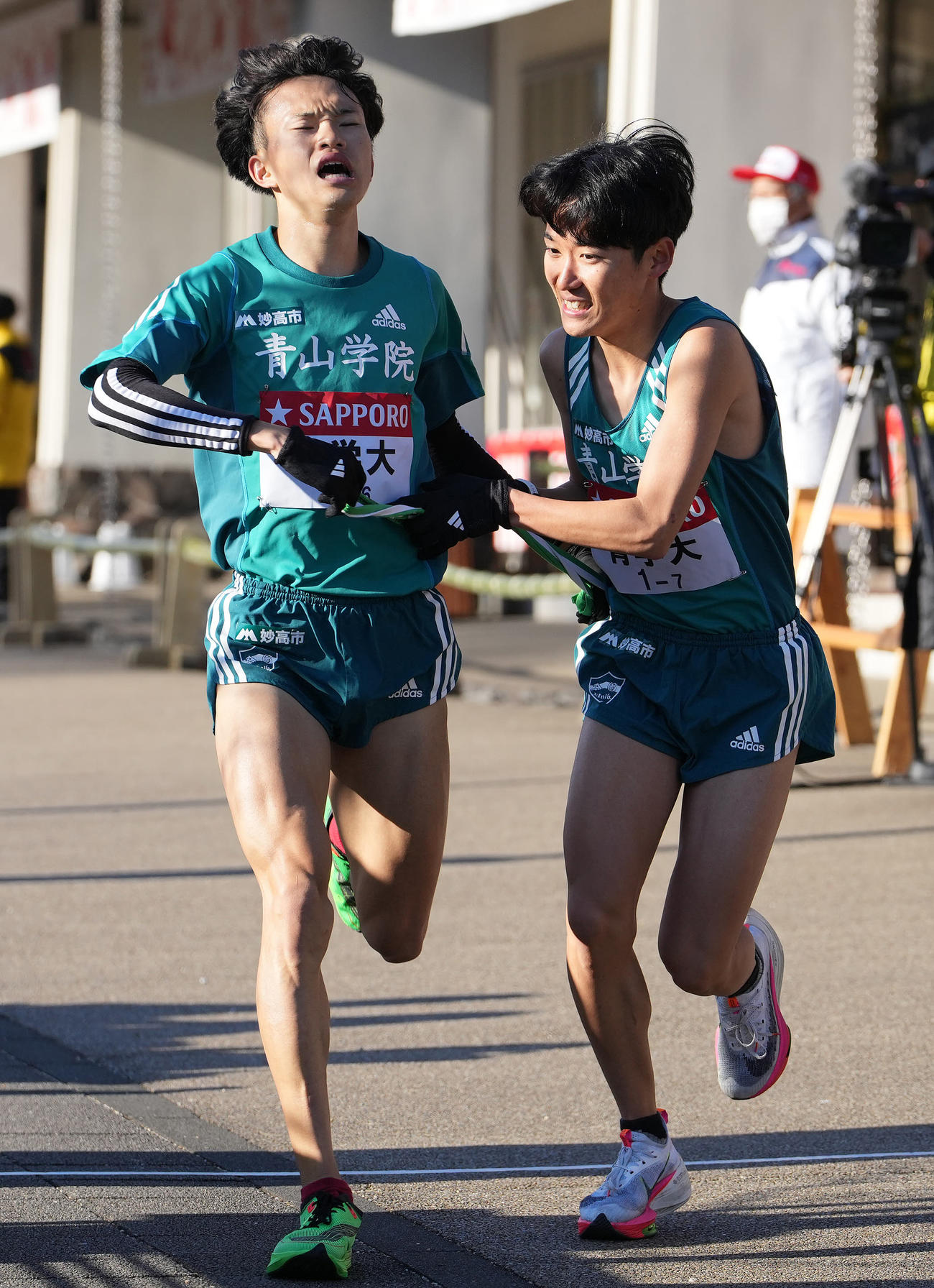 青学大6区西川（左）は小田原中継所で7区佐藤にたすきを渡す（撮影・鈴木みどり）