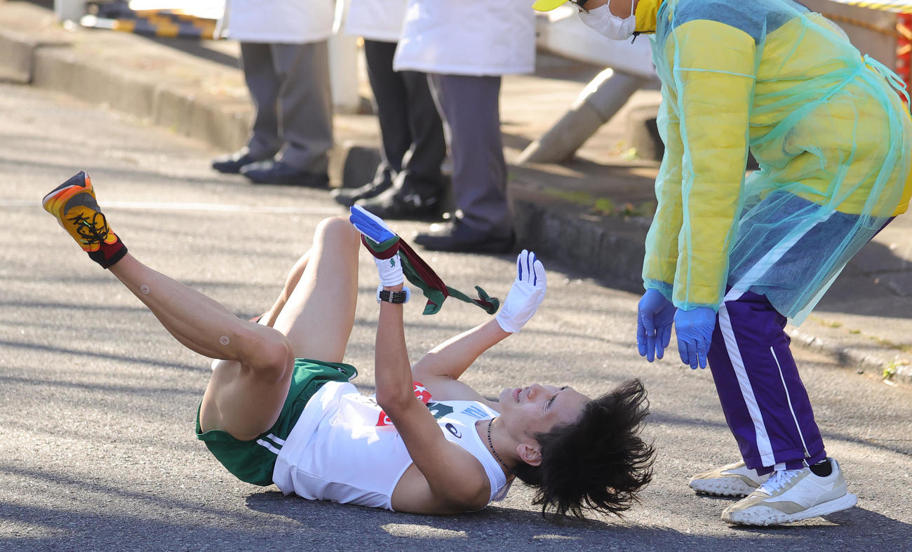 目前で10区が繰り上げスタートになった専大9区の南は、鶴見中継所に飛び込むとたすきを握りながら倒れ込んだ（撮影・野上伸悟）