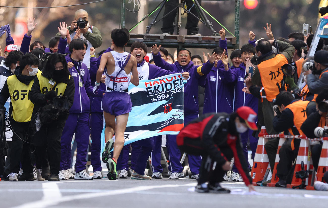 箱根駅伝総合優勝のゴールテープを切った駒大10区青柿（手前）を迎える大八木監督（中央右）とチームメート（代表撮影）