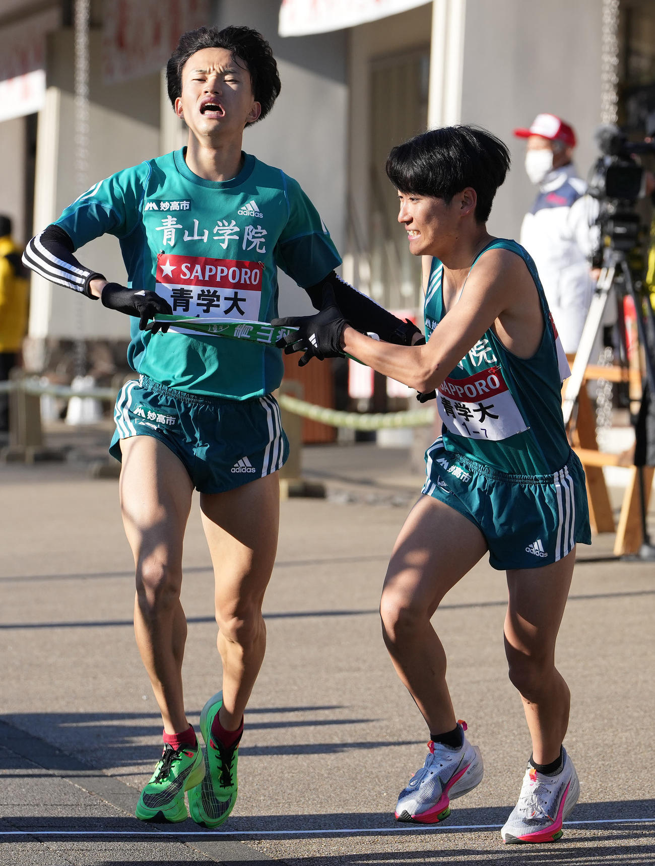 青学大6区西川（左）は小田原中継所で7区佐藤にたすきを渡す（撮影・鈴木みどり）