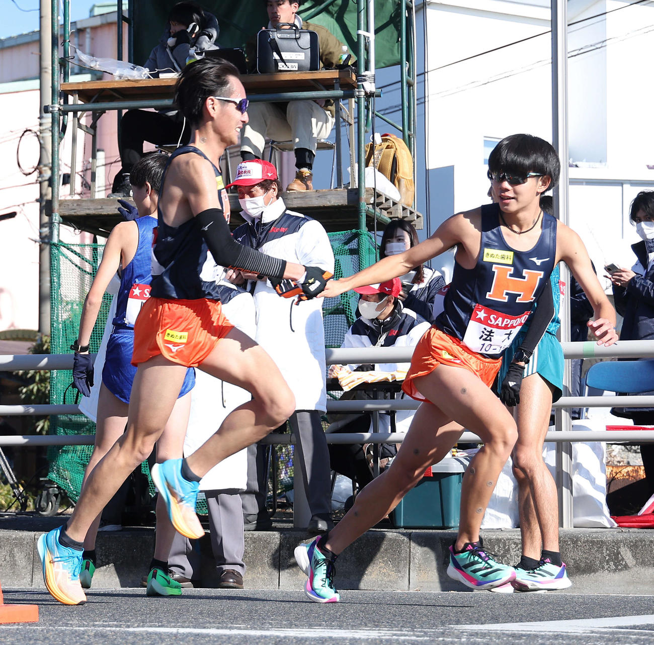 平塚中継所、6位でたすきをつなぐ法大7区宮岡（左）と8区宗像（撮影・河田真司）