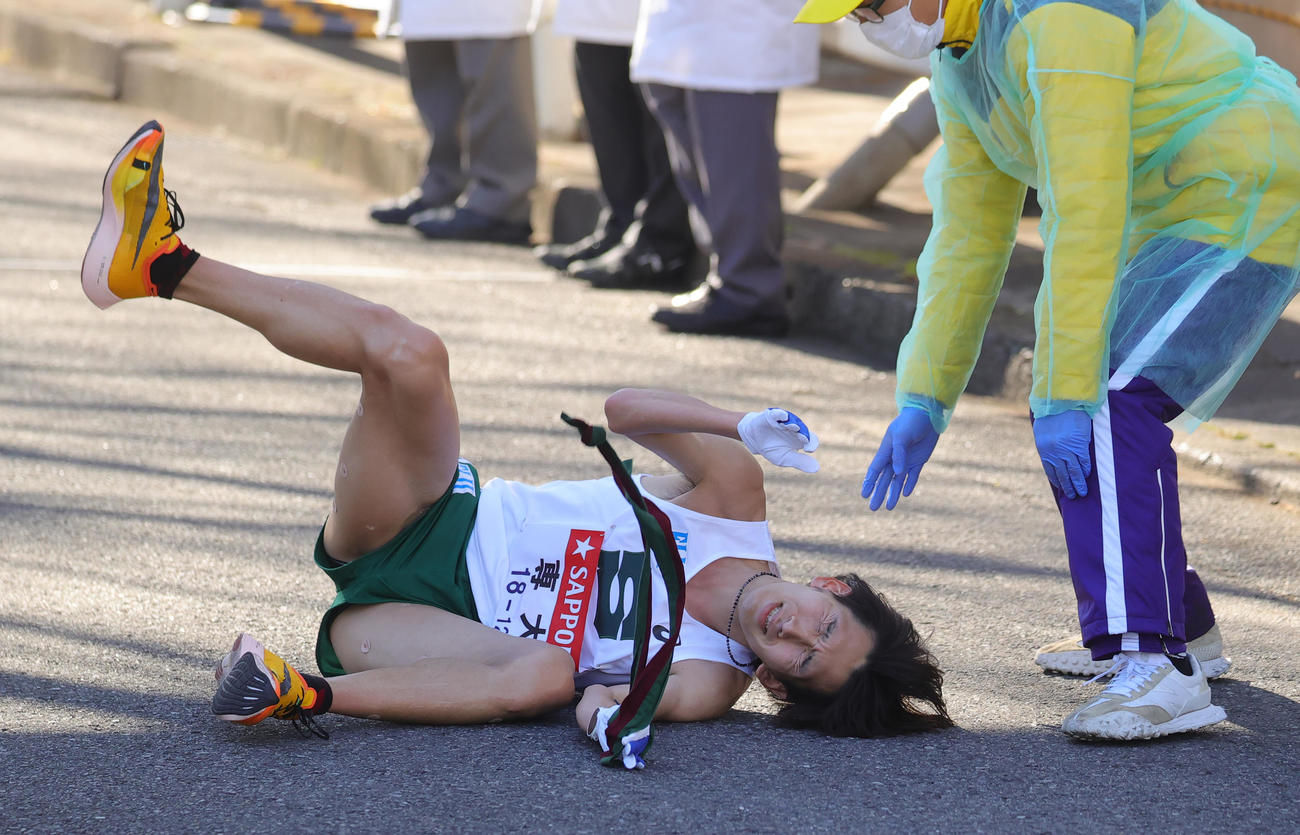 鶴見中継所でたすきを握りながら倒れ込んだ専大9区南（撮影・野上伸悟）