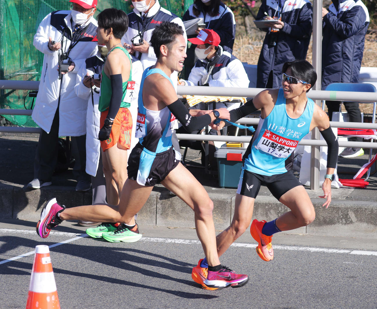 平塚中継所でたすきをつなぐ山梨学院大7区石部（左）と8区伊東（撮影・河田真司）