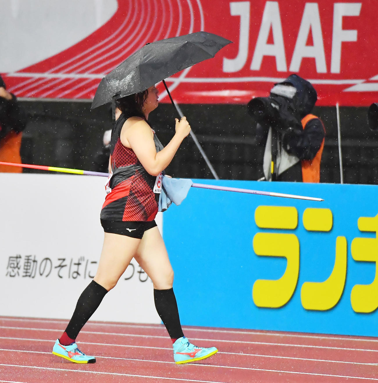 女子やり投げ　投てきを前に折りたたみ傘を差して移動する北口（撮影・清水貴仁）