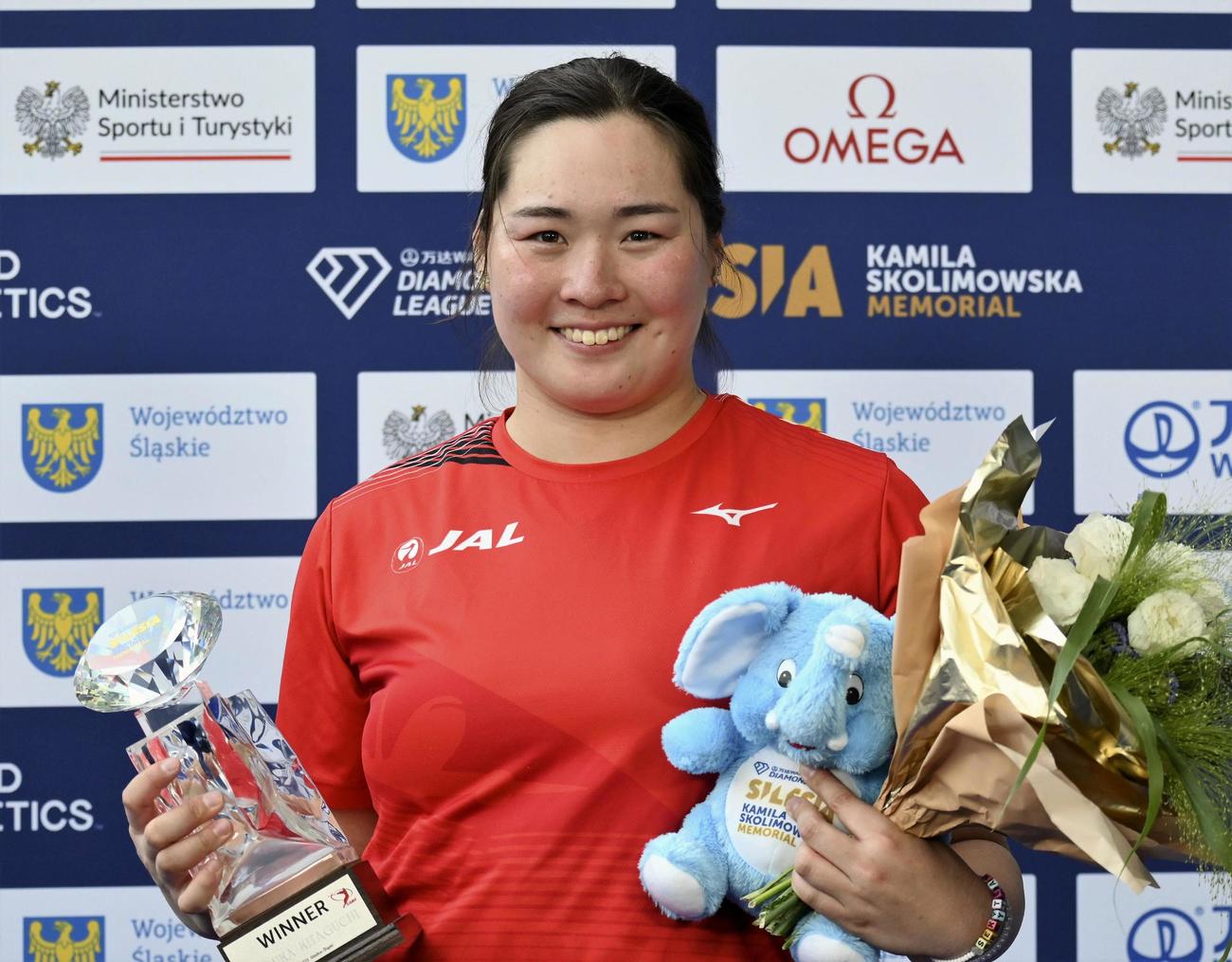 女子やり投げで67メートル04の日本新で通算4勝目を挙げ、トロフィーを手に笑顔の北口榛花（共同）