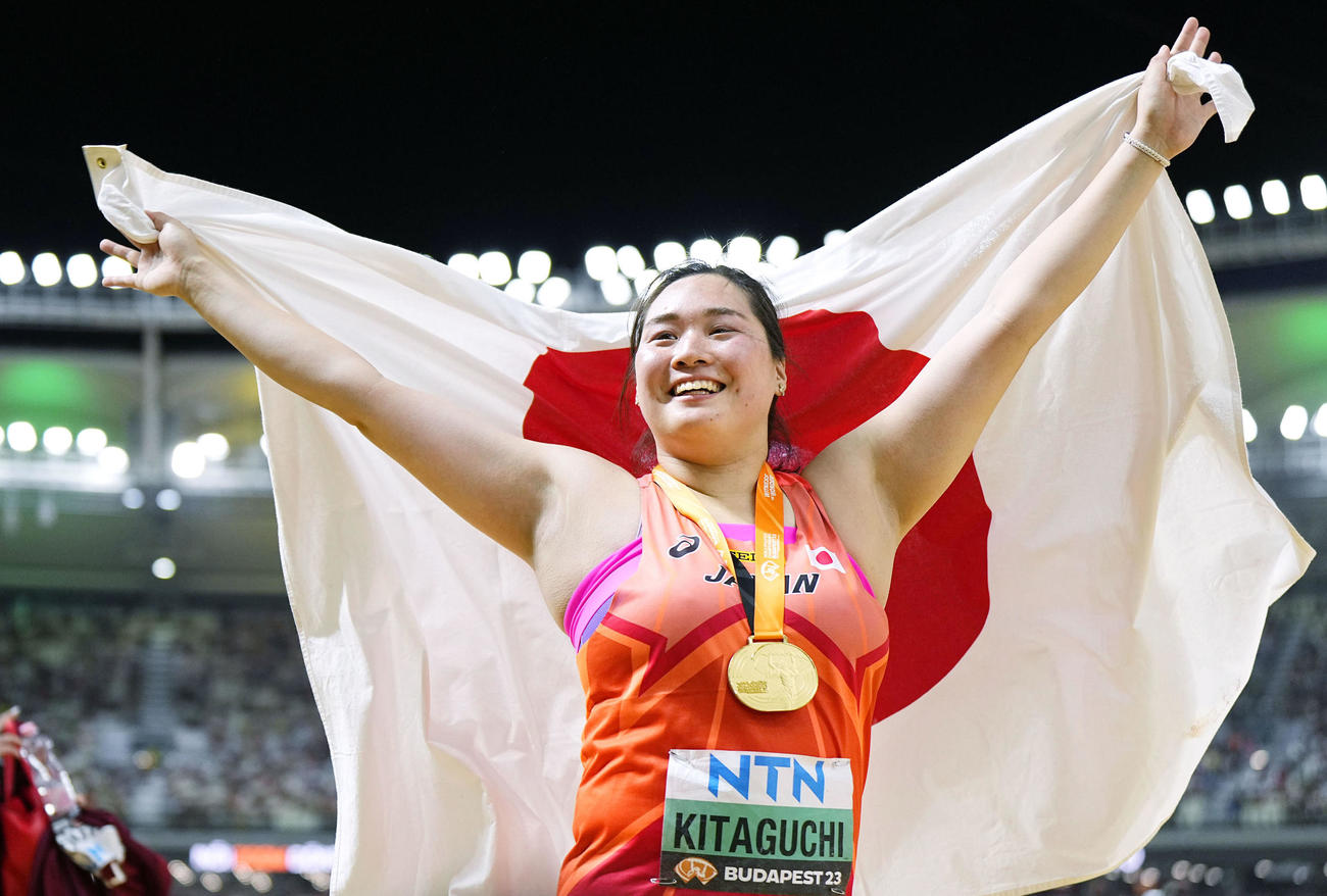 陸上の世界選手権女子やり投げで金メダルを獲得し、日の丸を掲げる北口榛花（共同）