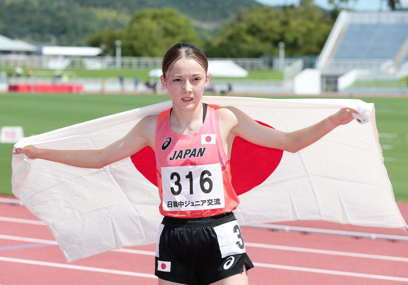 女子1500メートルで優勝したドルーリー朱瑛里は日の丸を手に写真に納まる（撮影・上山淳一）