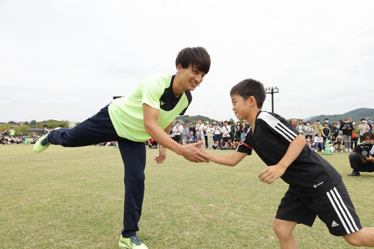 熊本・水俣市で開催された「地方企業からミライをスポーツフェス」で子どもたちと交流する陸上男子の橋岡（左）（UDN SPORTS提供）