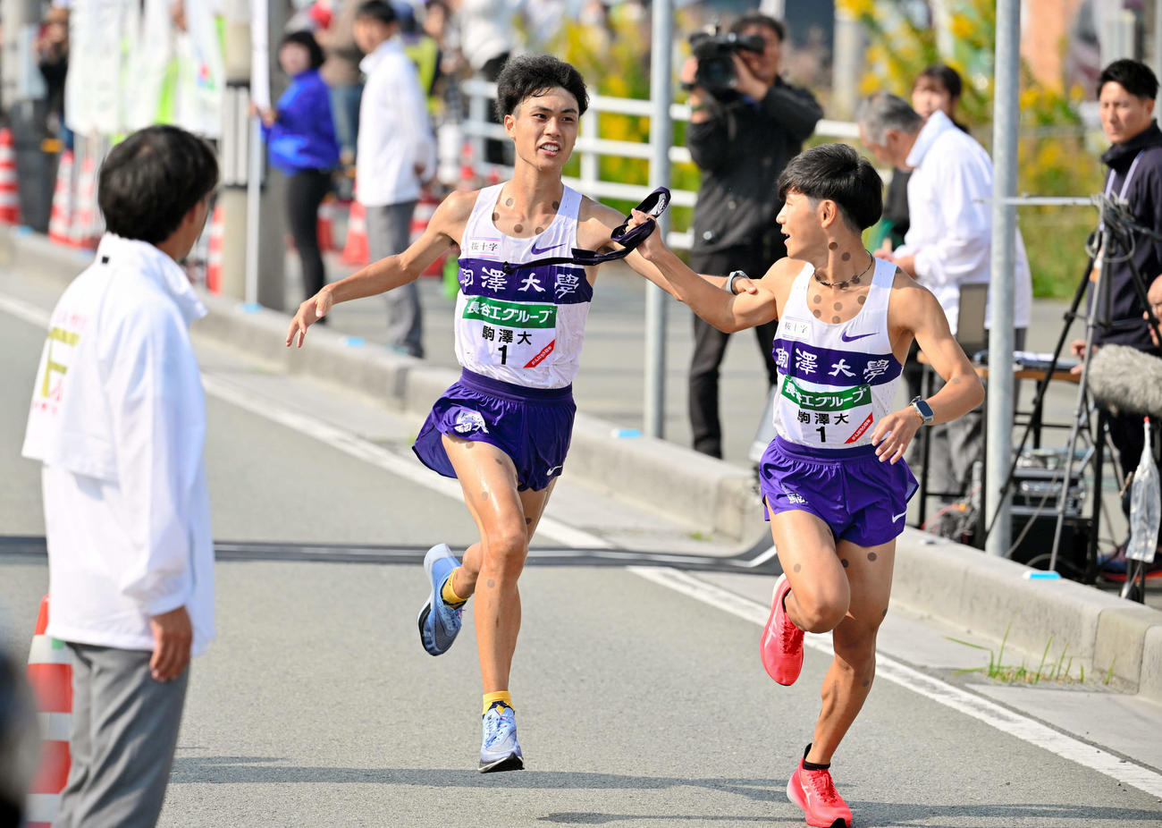 全日本大学駅伝　第7中継所で駒大8区のアンカー山川拓馬（右）にたすきを渡す7区の鈴木芽吹（代表撮影）
