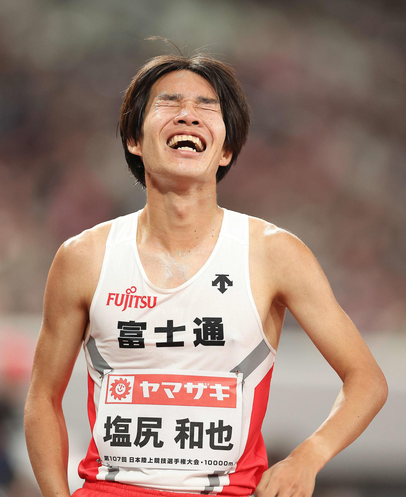 男子1万メートル　27分9秒80の日本新記録でフィニッシュし笑顔を見せる塩尻（撮影・河田真司）