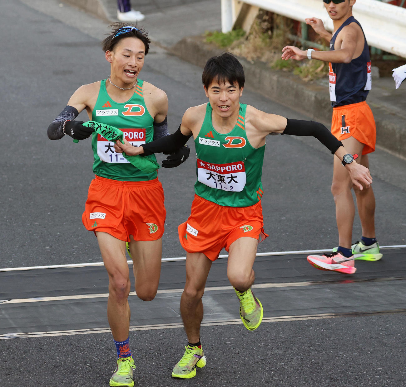 大東大1区西川（左）は2区久保田にたすきを渡す（撮影・大野祥一）