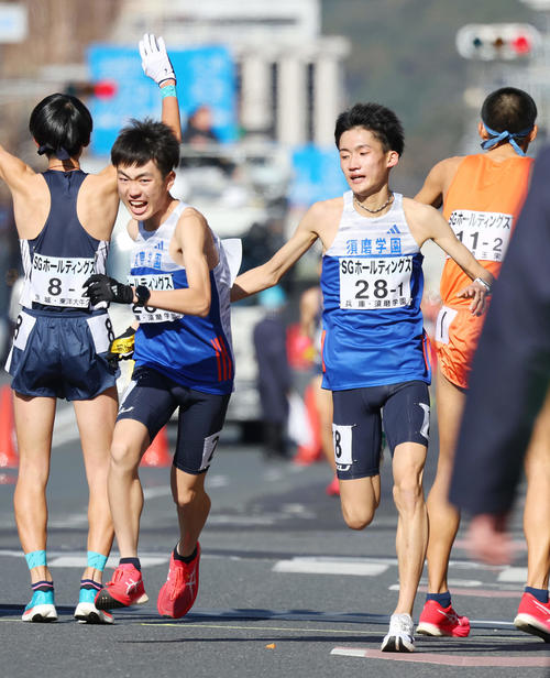 1位でたすきをつなぐ須磨学園1区の折田（右）と2区の藤岡（撮影・前田充）