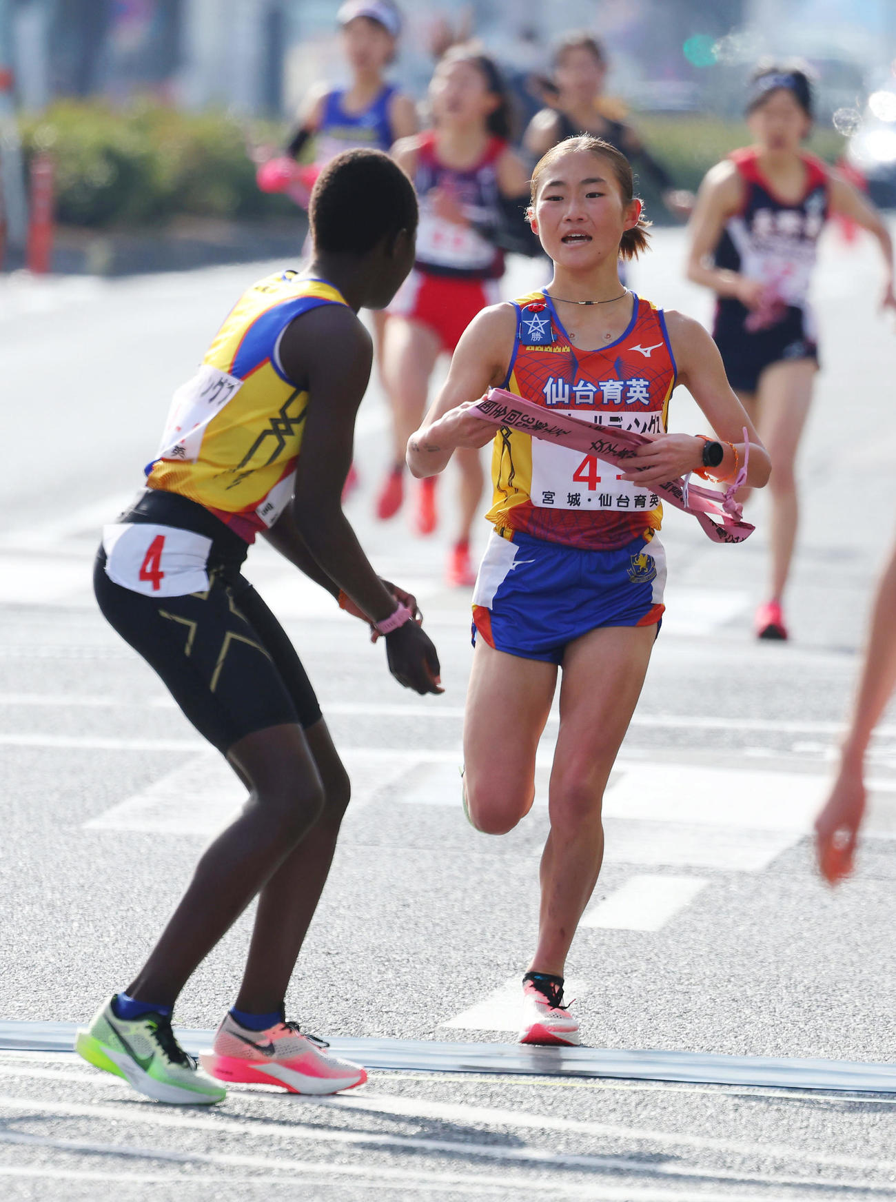 3位でたすきをつなぐ仙台育英1区の細川（右）と2区デイシー・ジェロップ（撮影・前田充）