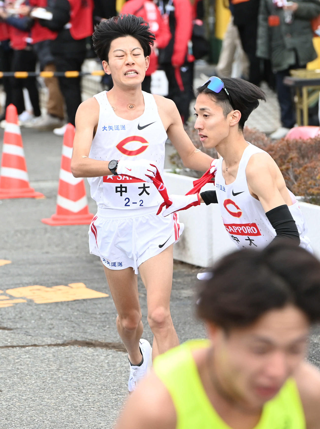 中大2区吉居大（後方）は3区中野にたすきを渡す（撮影・山崎安昭）