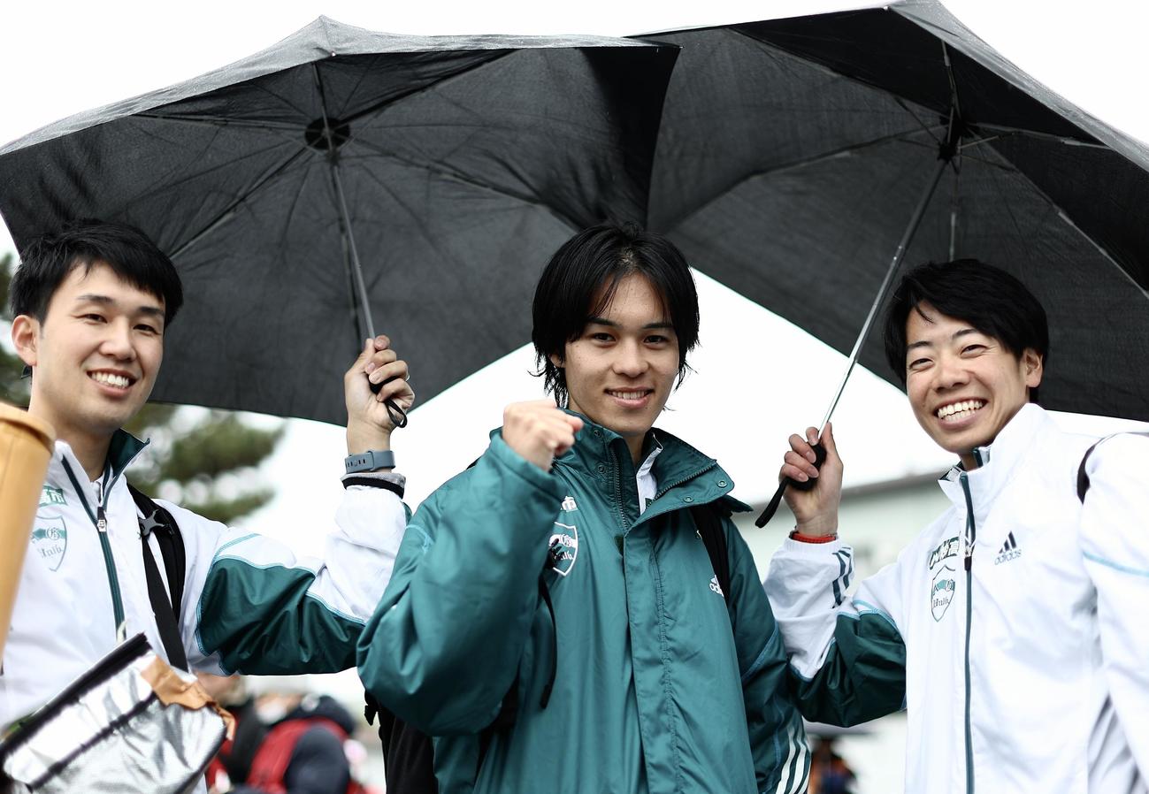 平塚中継所、仲間に傘をさしてもらいながらガッツポーズで写真に納まる青学大3区太田（中央）（撮影・河田真司）