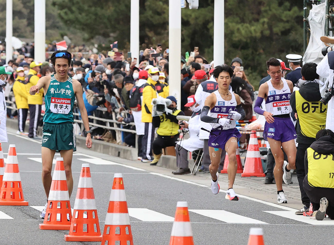 平塚中継所、トップでたすきをつなぎガッツポーズの青学大3区太田（左）。右は2位でたすきをつなぐ駒大3区佐藤。右から2人目は4区山川（撮影・河野匠）