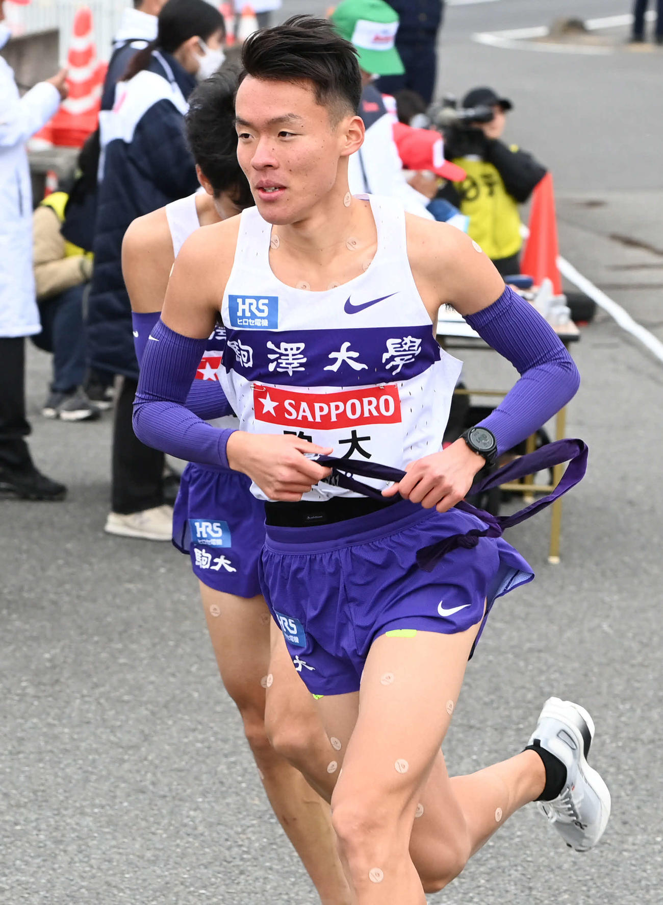 戸塚中継所から駆け出す駒大3区佐藤（撮影・山崎安昭）