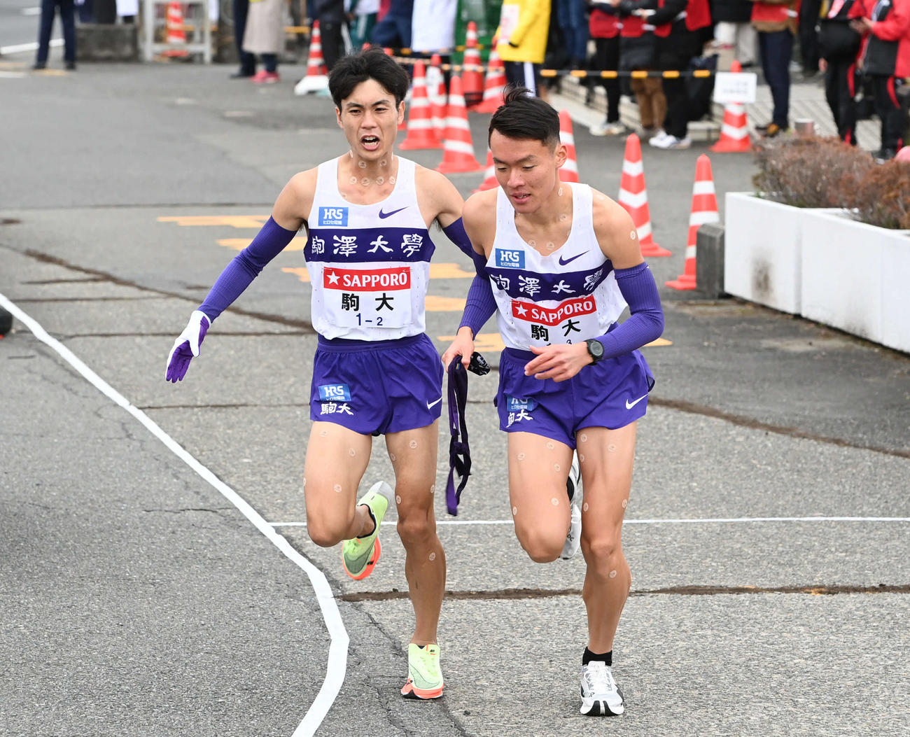 戸塚中継所にトップで駆け込んだ駒大2区鈴木（左）はたすきを渡した3区佐藤に声をかける（撮影・山崎安昭）