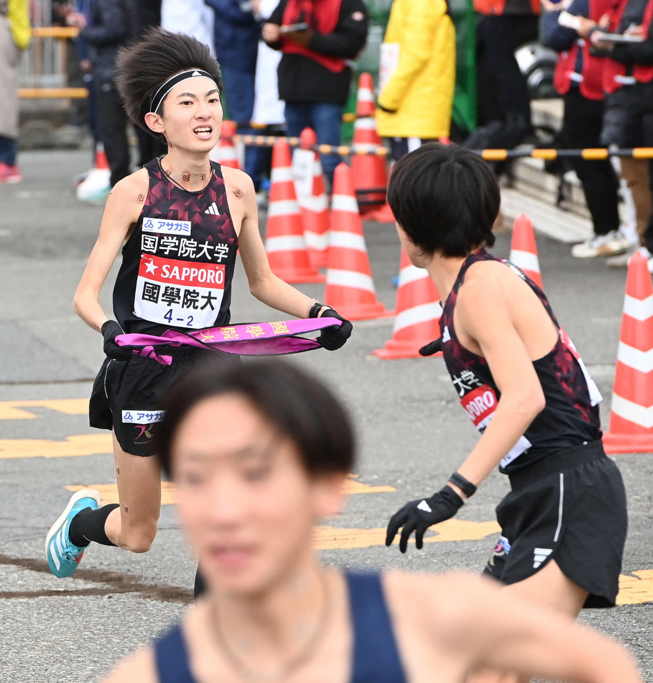 国学院大2区平林（左）は3区青木にたすきを渡す（撮影・山崎安昭）