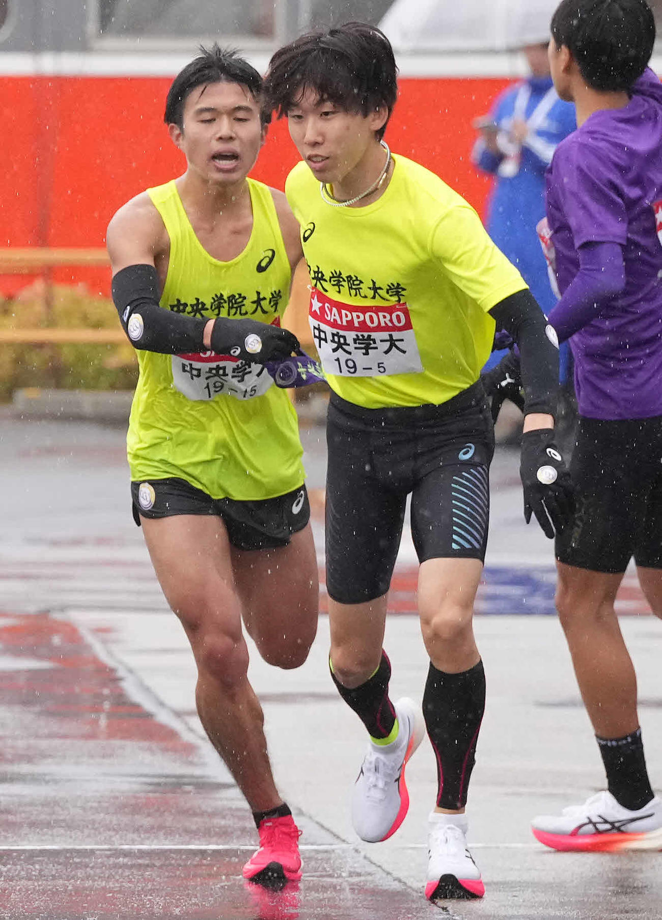 小田原中継所で5区柴田（右）にたすきを渡す中央学院大4区黒岩（撮影・鈴木みどり）