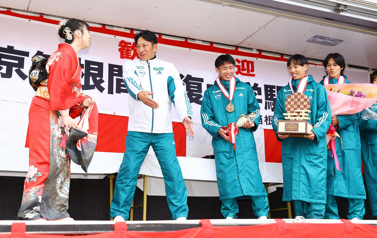 往路優勝し記念撮影でプレゼンターの女性に真ん中に来るよう促す青学大・原監督（左から2人目）（撮影・垰建太）