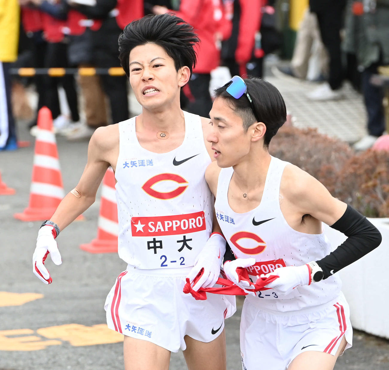中大2区吉居大（左）は3区中野にたすきを渡す（撮影・山崎安昭）