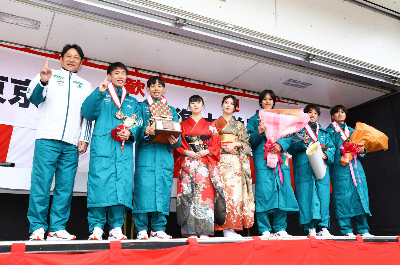 往路優勝しプレゼンターの女性と記念写真に納まる青学大の、左から原晋監督、1区荒巻、2区黒田、2人おいて、3区太田、4区佐藤、5区若林（撮影・垰建太）