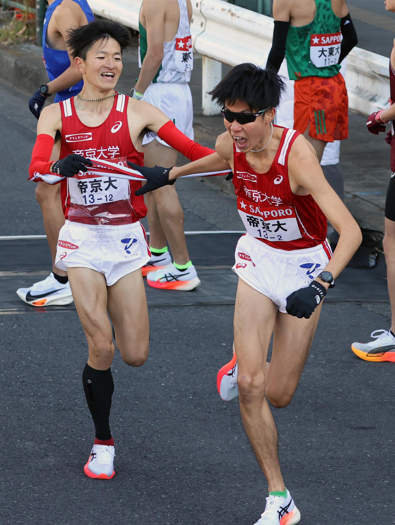 帝京大1区西脇（左）は2区山中にたすきを渡す（撮影・大野祥一）
