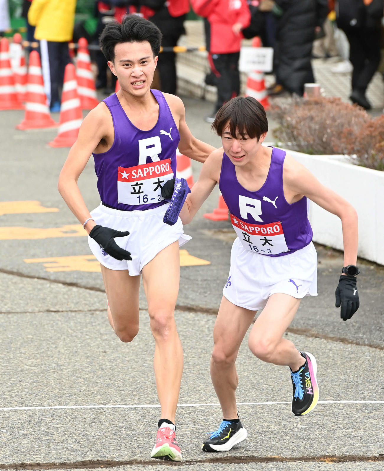 立大2区国安（左）は3区馬場にたすきを渡す（撮影・山崎安昭）