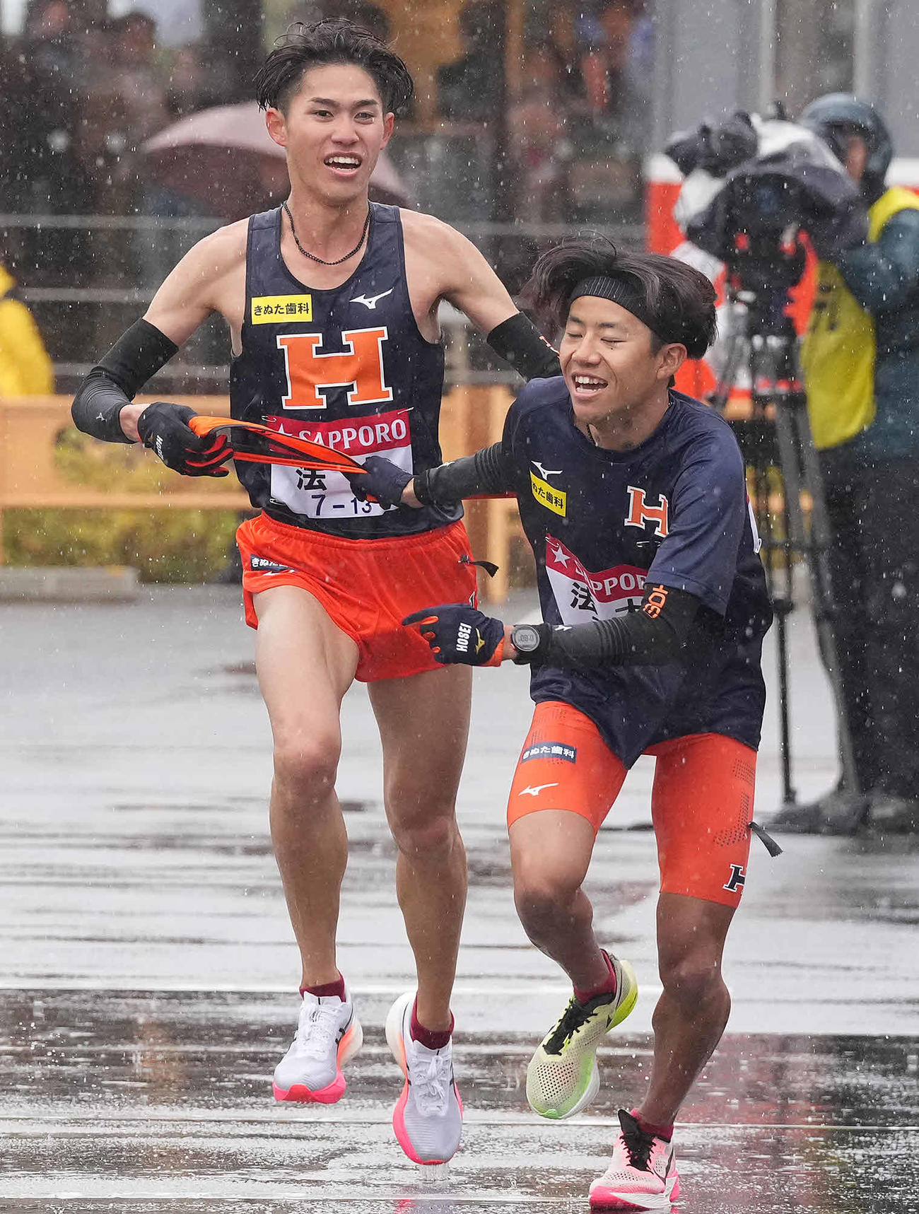 小田原中継所で5区細迫（右）にたすきを渡す法大4区小泉（撮影・鈴木みどり）