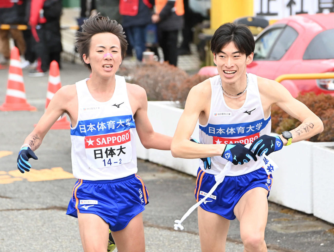 日体大3区漆畑（右）は2区山口からたすきを受け取る（撮影・山崎安昭）