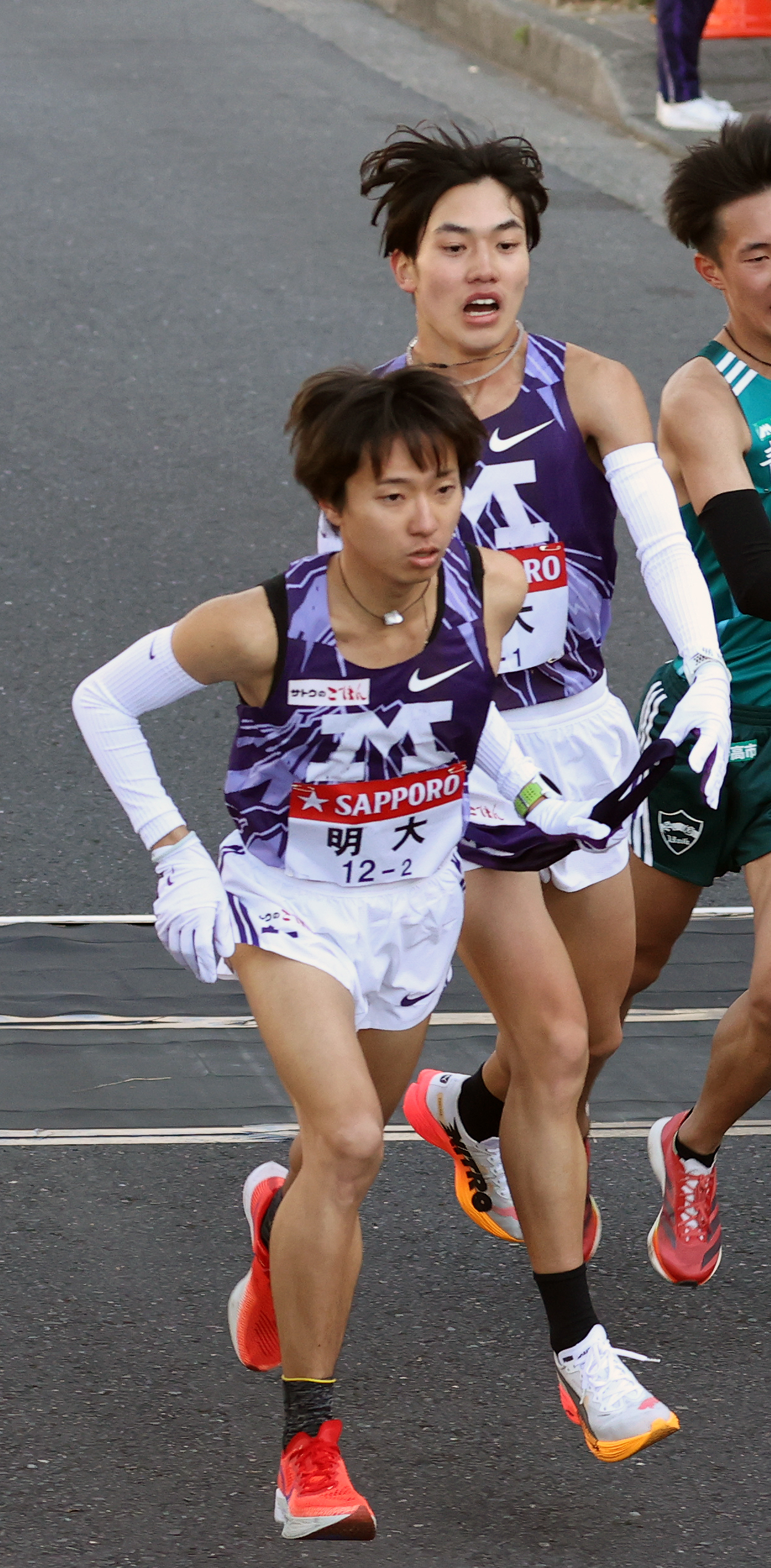 明大1区大湊（左から2人目）は2区児玉にたすきを渡す（撮影・大野祥一）