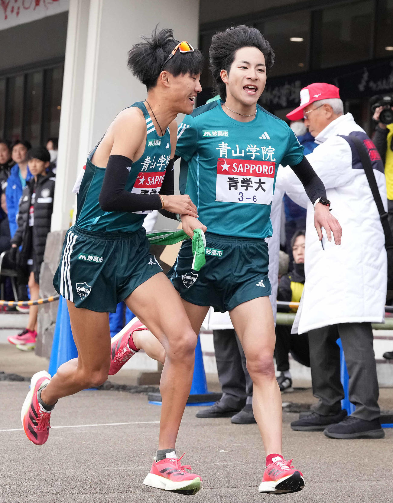 小田原中継所で7区山内（左）にたすきを渡す青学大6区野村（撮影・鈴木みどり）
