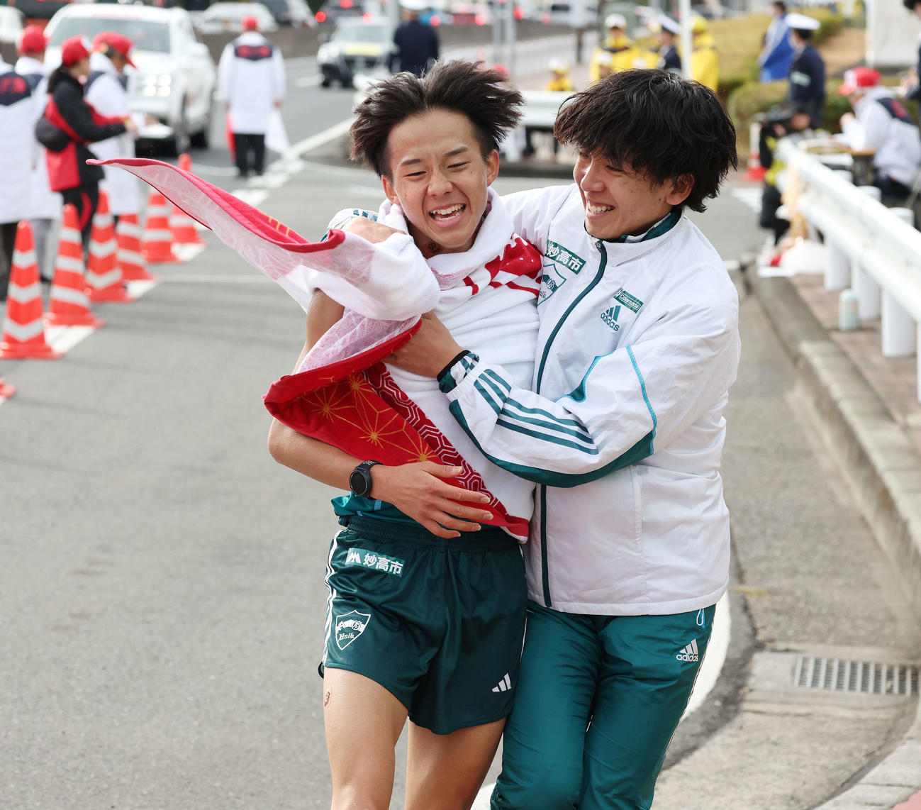 戸塚中継所をトップでタスキをつなぎ、仲間に笑顔で迎えられる青学大8区塩出（左）（撮影・宮地輝）