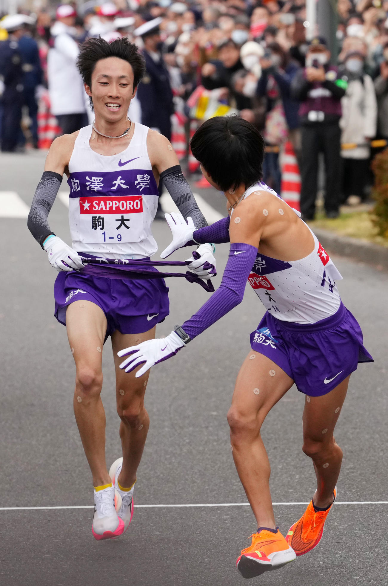 鶴見中継所で10区庭瀬俊（右）にたすきを渡す駒大9区花尾（撮影・横山健太）