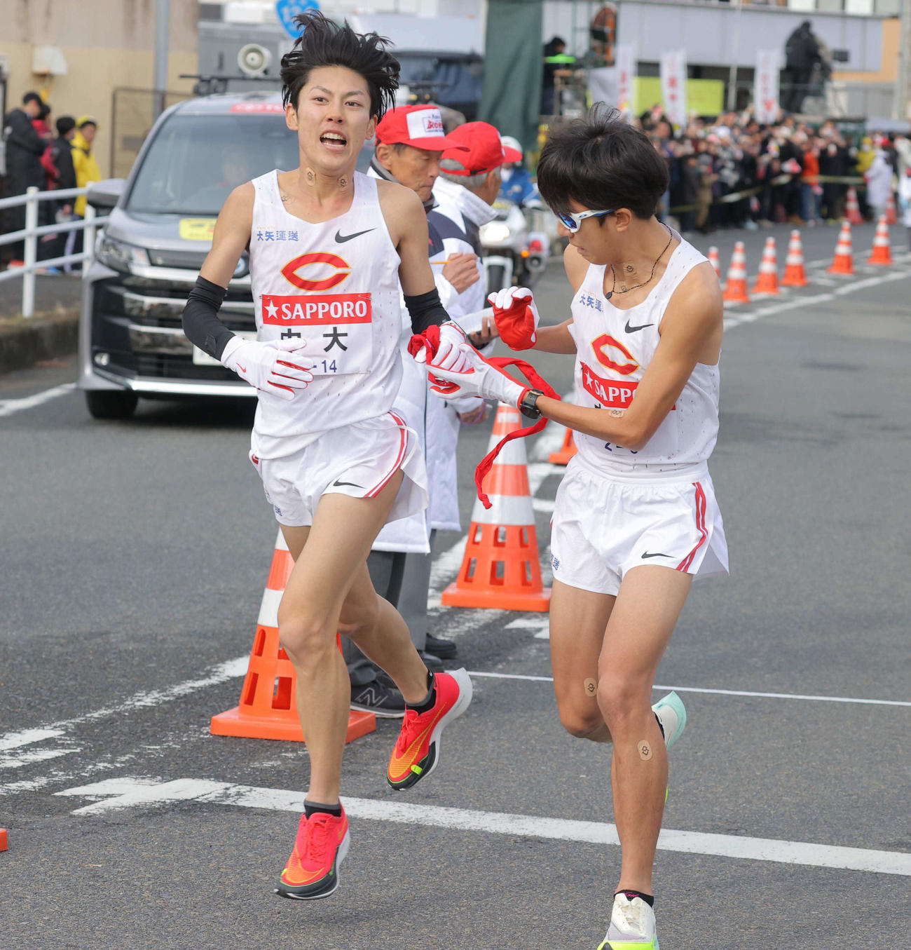 平塚中継所でタスキをつなぐ中大7区の吉居駿（左）と8区の阿部（代表撮影）