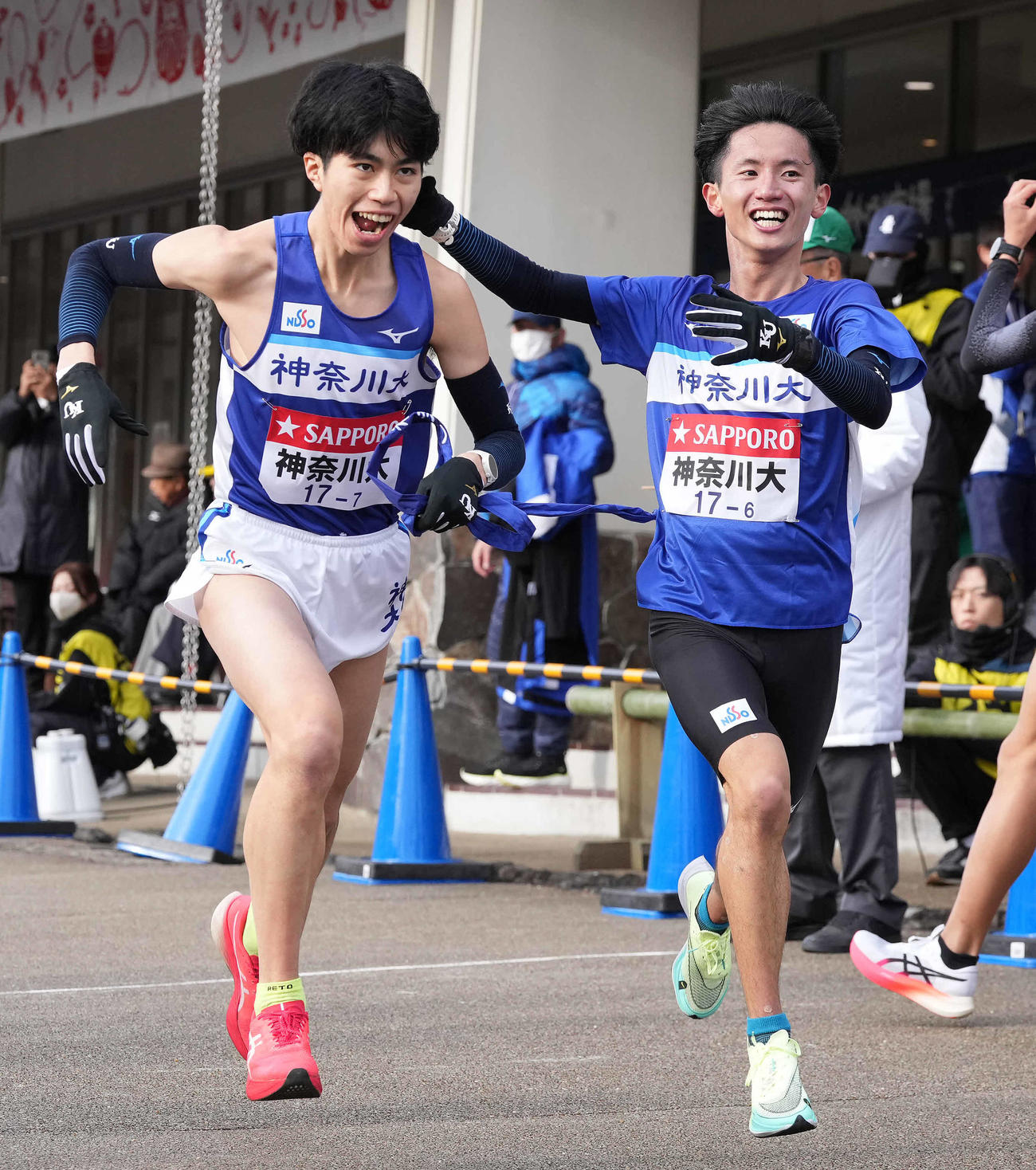 小田原中継所で7区新妻（左）にたすきを渡す神奈川大6区大岩（撮影・鈴木みどり）