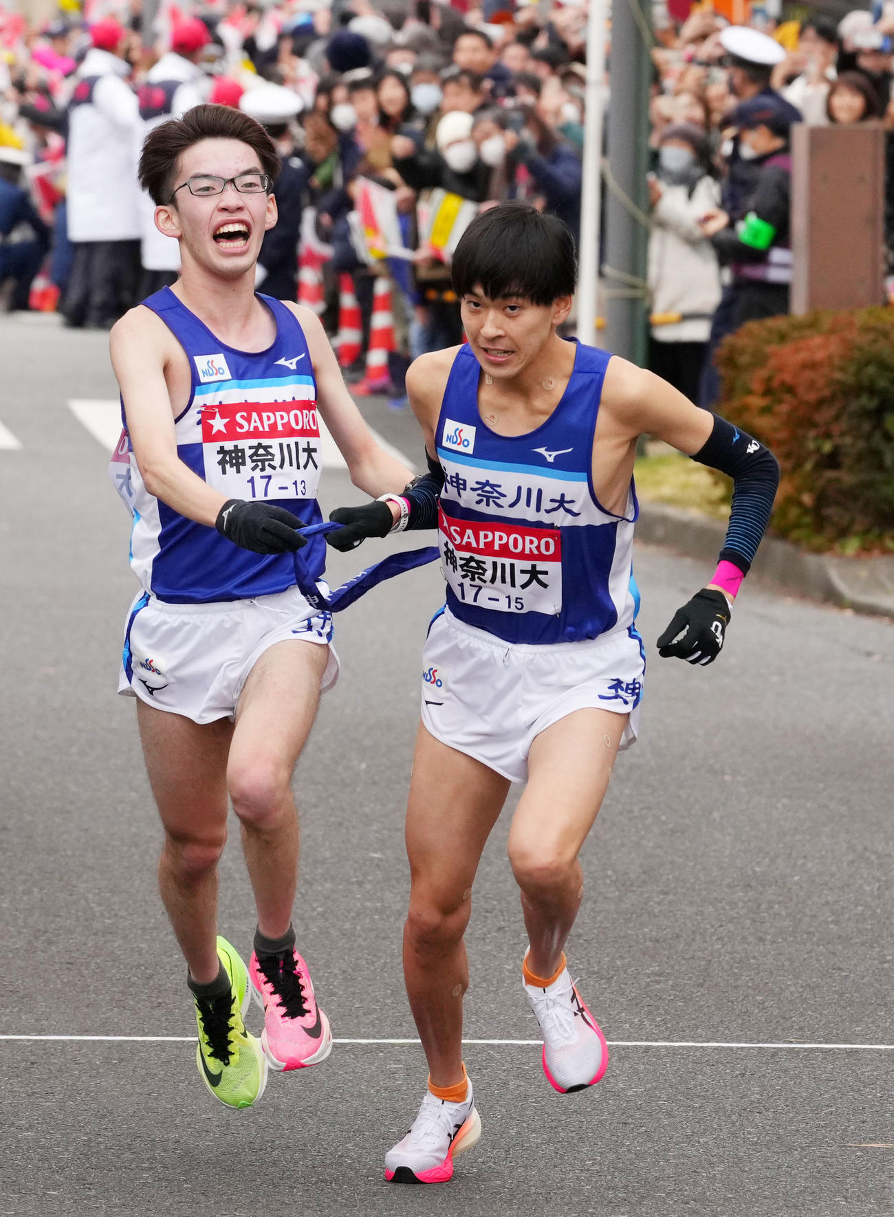 鶴見中継所で10区酒井（右）にたすきを渡す神奈川大9区佐々木（撮影・横山健太）