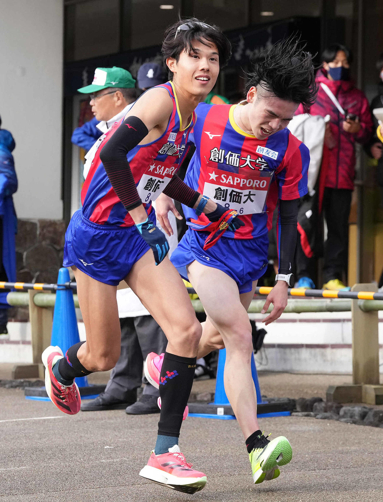 小田原中継所で7区石丸（左）にたすきを渡す創価大6区川上（撮影・鈴木みどり）