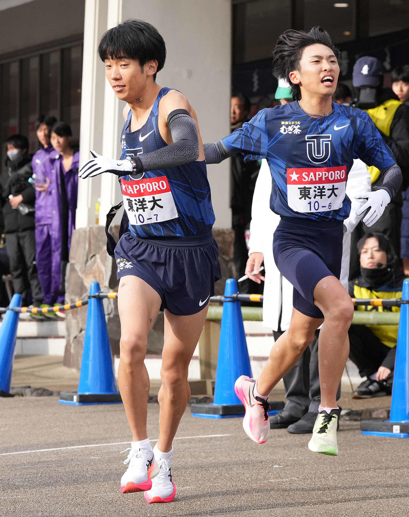 小田原中継所で7区熊崎（左）にたすきを渡す東洋大6区西村（撮影・鈴木みどり）