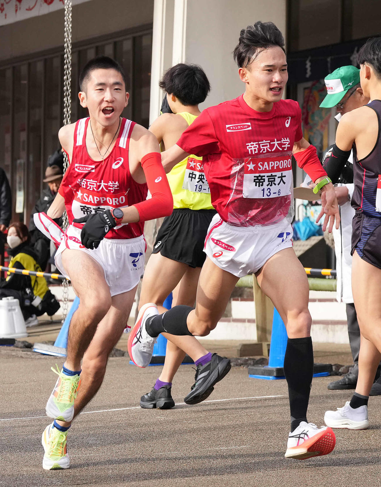 小田原中継所で7区小野（左）にたすきを渡す帝京大6区大吉（撮影・鈴木みどり）