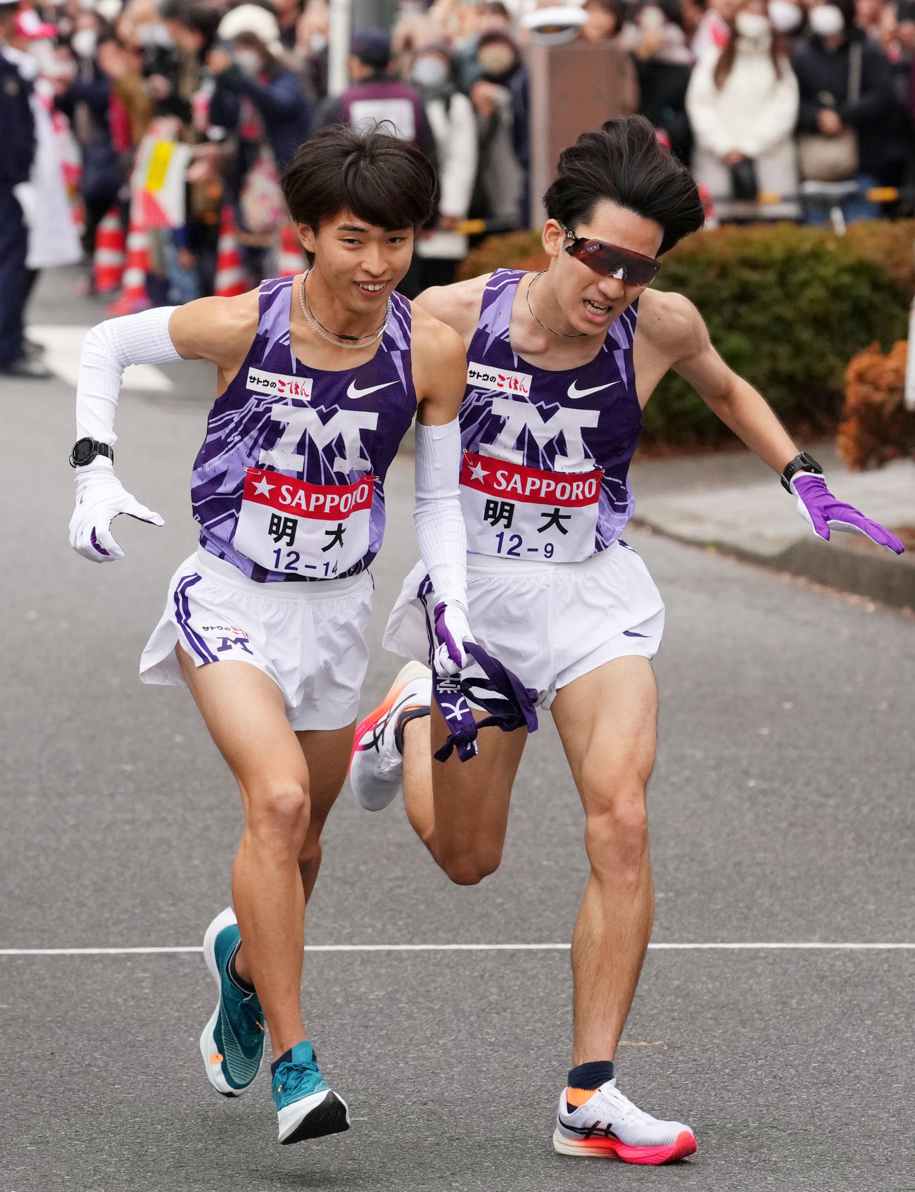 鶴見中継所で10区古井（左）にたすきを渡す明大9区鈴木（撮影・横山健太）