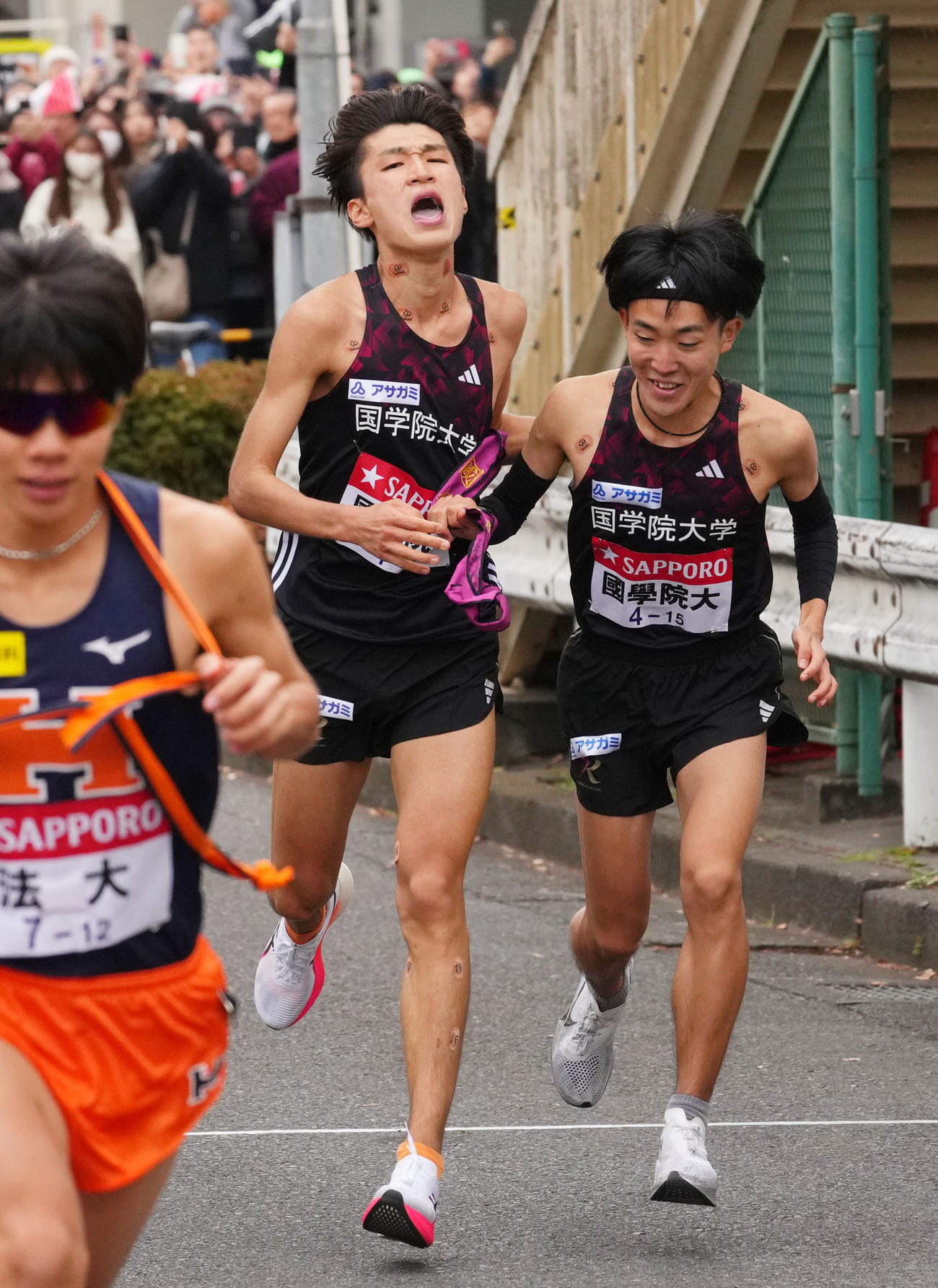鶴見中継所で10区高山（右）にたすきを渡す国学院大9区吉田（撮影・横山健太）